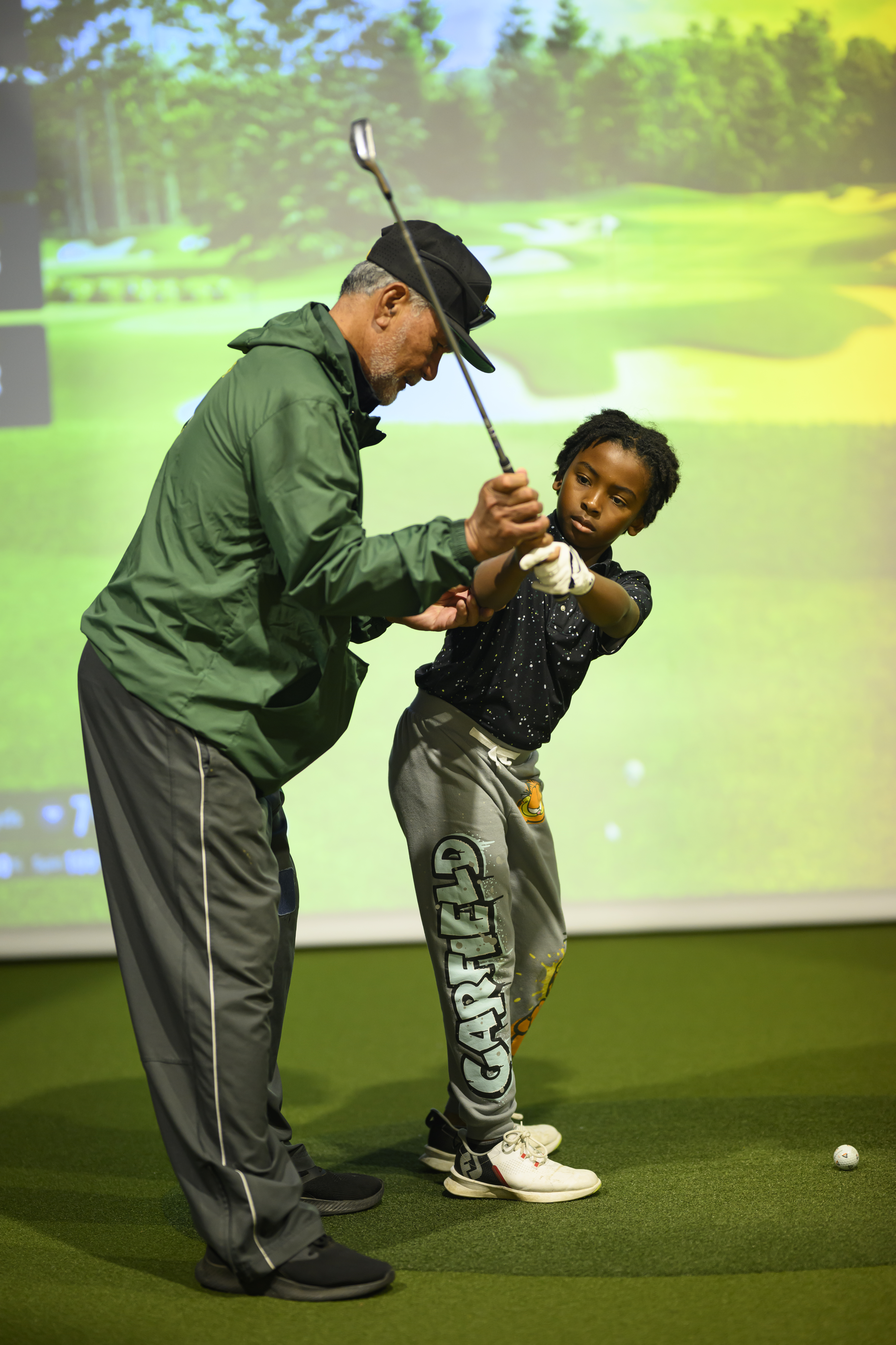 Instructor giving swing feedback in front of simulator screen at The Lab 301